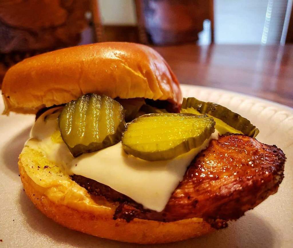 Caribeque chicken sandwich featuring pepper jack cheese and dill pickle chips on a brioche bun